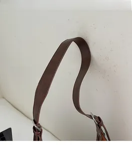 Détail de la bandoulière large en daim marron avec boucle en métal argenté réglable