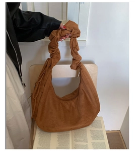 Detail of brown suede hobo bag with unique scrunchie handle and tassel decoration