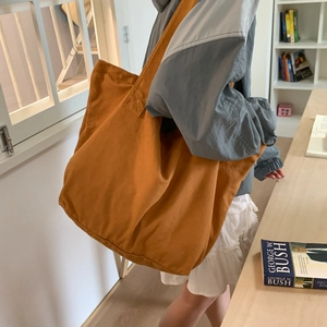 Detail view of large brown canvas tote bag featuring wide shoulder straps and spacious design
