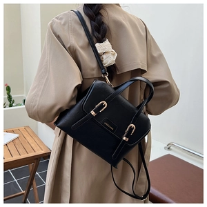 Rear view of model wearing a black pebbled leather multi-way backpack with gold hardware