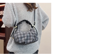 Detail of checkered crossbody bag with scrunchie handle on model's shoulder