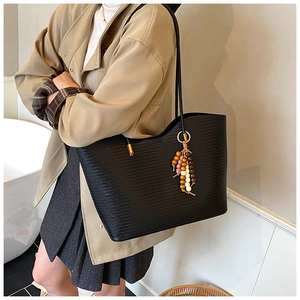 Détail du sac cabas noir avec texture tissée, garniture dorée et perles en bois rétro