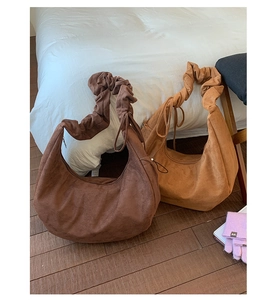 Detail of vintage ruched shoulder straps on suede hobo bags in coffee and caramel