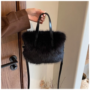 Detail of plush black faux fur handbag featuring soft texture and leather handles