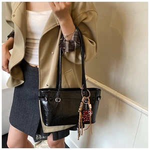 Detail view of black glossy shoulder bag with silver hardware and leopard print charm