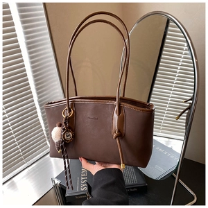 Close-up of vintage brown leather tote bag with brand logo and soft shadow lighting