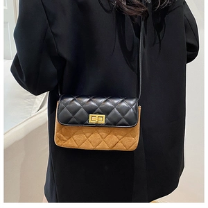 Detail view of the quilted texture and golden twist lock on a two-tone crossbody bag