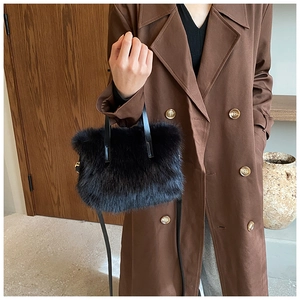 Close-up of black faux fur handbag with leather handle and gold hardware detail