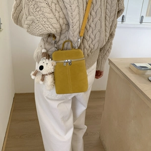 Detail of yellow frosted crossbody bag with silver zipper and cute teddy bear pendant
