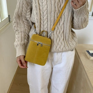 Model wearing a bright yellow frosted suede bucket bag with crossbody strap and silver zipper