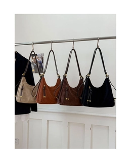 Detail view of four suede hobo bags in beige, camel, brown and black with fringe tassels