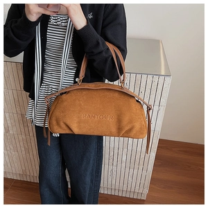 Detailed view of brown suede bag featuring embossed logo and side tassel decoration