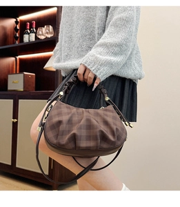 Detailed view of dark brown plaid pleated dumpling bag with cloud-like handle and strap
