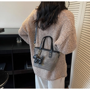 Detail of grey marble texture crossbody bag with black puppy charm and gold hardware
