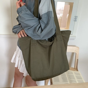 Detail view of large olive green canvas tote bag worn over shoulder for daily use