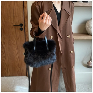 Close-up of fluffy black faux fur texture and leather handle on a winter crossbody bag