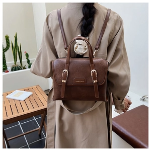 Detail view of brown vintage backpack with leather texture and dual metal buckles on model