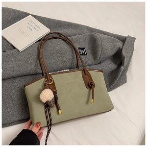 Close-up of Morandi green suede tote bag with brown leather handles and plush charm