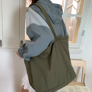 Close-up of olive green canvas tote bag shoulder strap and spacious side view on model