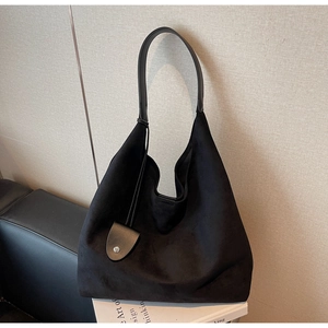 Close-up of black suede hobo bag with a minimalist leather pendant and long strap