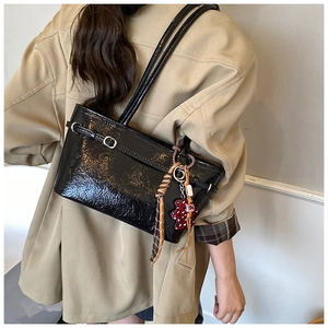 Detail of glossy black shoulder bag with leopard bear charm and checkered silk scarf