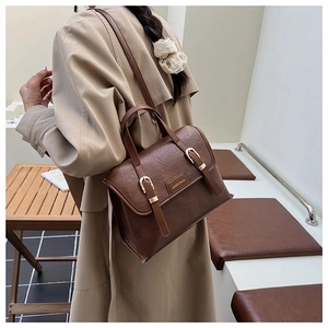 Brown vintage leather crossbody bag with double buckle straps and metal brand logo
