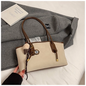 Detail of cream tote bag with brown leather trim and plush ice cream keychain accessory