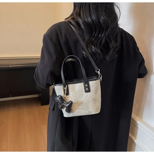 Detail of grey marble textured tote bag with black strap and dog charm on a model