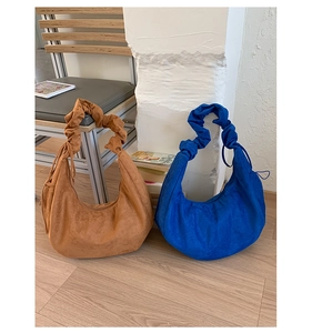 Detail view of crescent shoulder bags in brown and royal blue with pleated straps