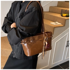 Detailed view of vintage dark brown glossy shoulder bag with heart tassel charm
