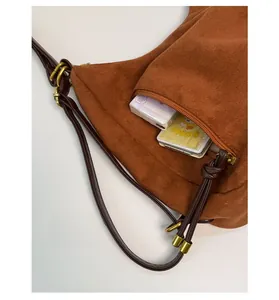 Detail of brown suede shoulder bag with side zipper pocket and vintage gold hardware