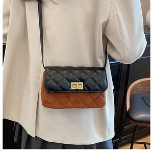 Detail of quilted two-tone crossbody bag with golden twist lock on a stylish blazer outfit