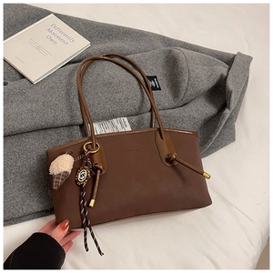 Detailed view of brown matte leather tote bag featuring a cute ice cream plush charm