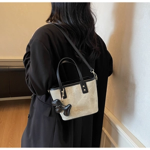 Detail of a minimalist crossbody bucket bag with M.Delan logo and cute puppy pendant