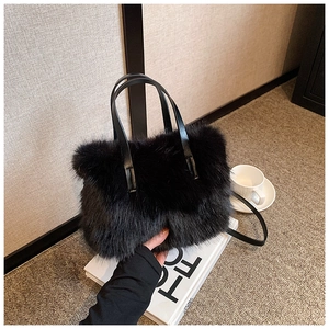 Detail of black faux fur handbag with leather handles on minimalist white prop books