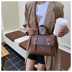 Detail of vintage brown PU leather convertible bag with gold buckles and adjustable strap
