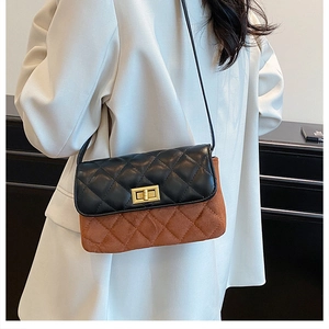 Detail of a chic quilted crossbody bag featuring a two-tone texture with gold twist lock