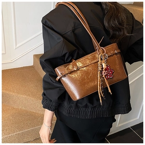 Detail of retro brown hobo bag with pleated texture and decorative leopard floral pendant