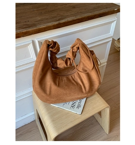 Detail of caramel brown suede hobo bag featuring a stylish ruched scrunchie handle