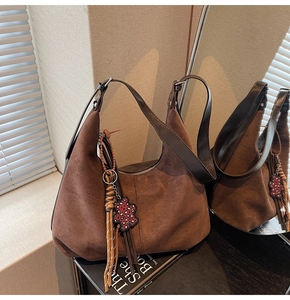 Gros plan détaillé du sac hobo en daim marron avec breloque ours et pompon chic