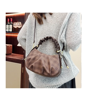 Close-up of brown plaid handbag featuring a scrunchie handle and gold hardware
