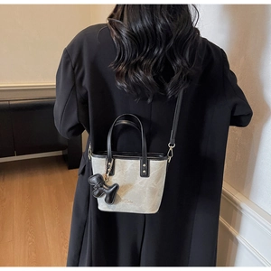 Crossbody tote bag with black trim and puppy charm worn over a black blazer back view