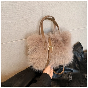 Detail of plush brown faux fur handbag with leather straps and gold metal buckles