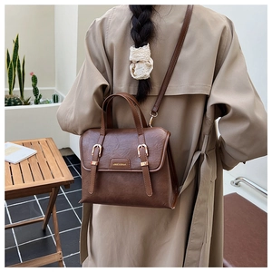 Detail view of vintage brown leather backpack worn by model with khaki trench coat