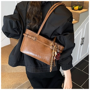 Detail of a brown glossy leather shoulder bag with tassel and heart charm decoration