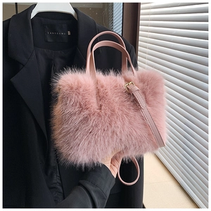 Close-up of pink faux fur handbag with leather handles and detachable shoulder strap