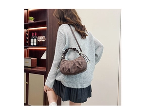Brown plaid hobo bag with ruched handle and crescent shape in a lifestyle setting