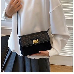 Detail of black quilted shoulder bag featuring gold twist lock and mixed leather texture