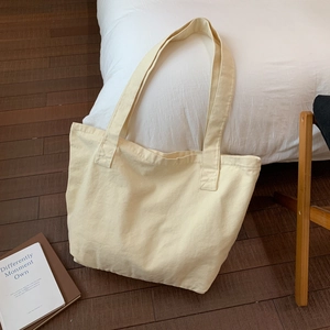 Close-up of minimalist beige canvas tote bag with thick durable texture and wide straps