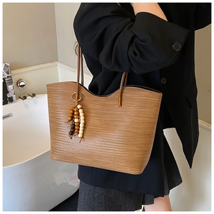 Détail du sac fourre-tout en paille marron avec breloque perlée et lanières en cuir